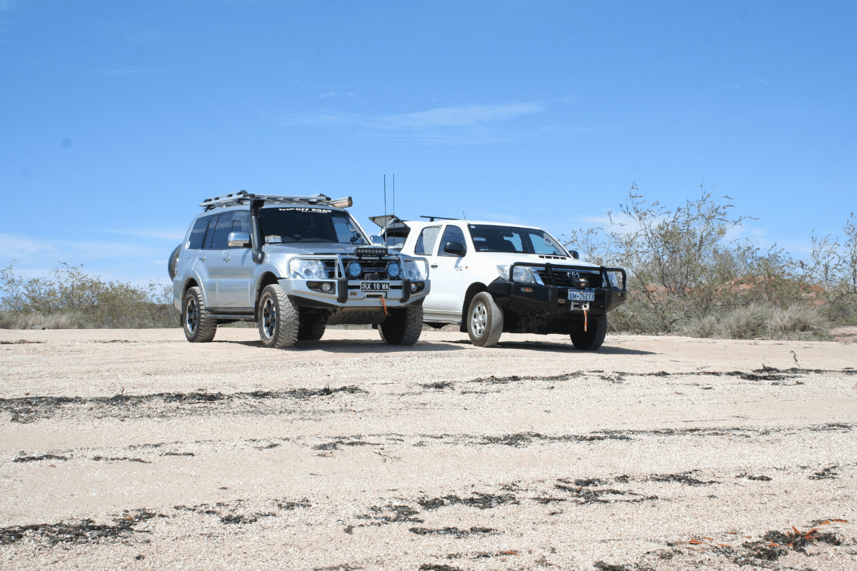 Silver 4WD and White 4WD parked on top of a white sand hill with dry bush and blue sky in the background part of the 4WD Course Perth WA