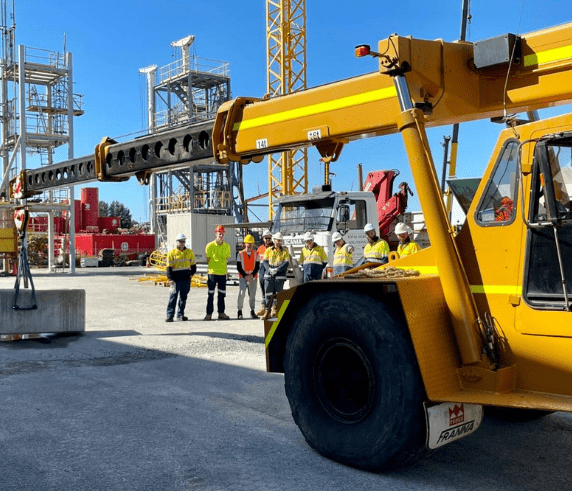 Operate a Non-Slewing Mobile Crane (Greater Than 3 Tonnes). A yellow non-slewing mobile crane on a construction site with students