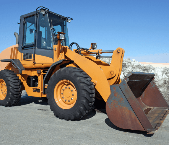 Conduct Civil Construction Wheeled Front End Loader Operations. Orange wheeled front-end loader with a large bucket, ready for operation on a civil construction site