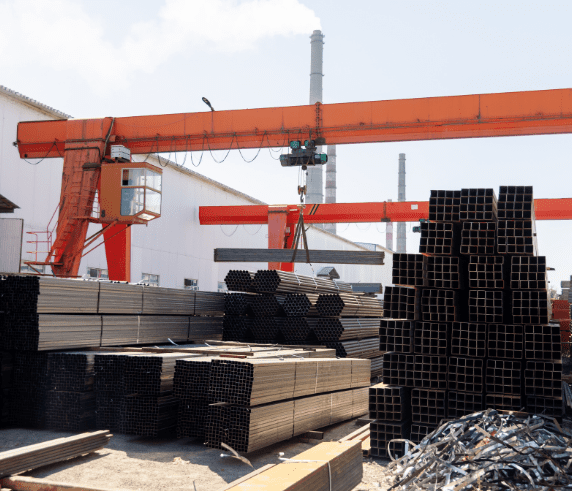 Operate a Bridge and Gantry Crane. An overhead crane lifting heavy steel materials at an industrial manufacturing yard.