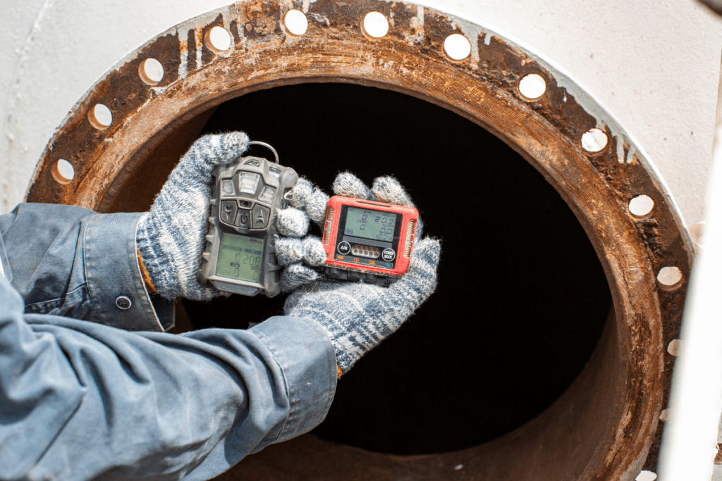 Saferight's Gas Safety personnel holding up a gas tester In front of an open gas pipeline performing a GAS TEST during the Saferight Gas Test Atmosphere Training Perth WA - Gas Testing Course