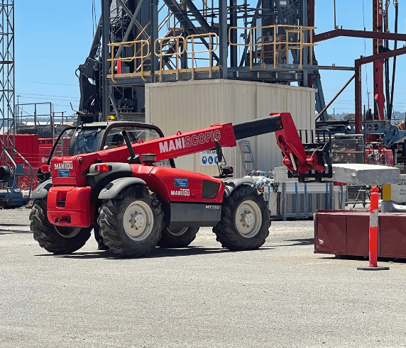 Student learning to navigate telehandler operations in Telehandler Ticket Perth. A telescopic materials handler positioned on Saferight's training course site with industrial structures in the background