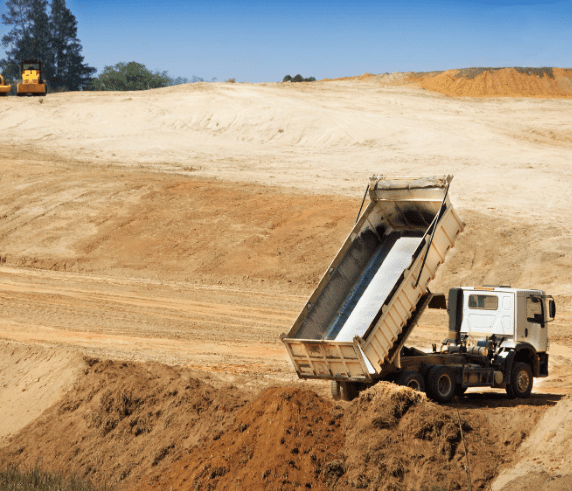 Conduct Tip Truck Operations. Tip truck unloading soil on a large construction site