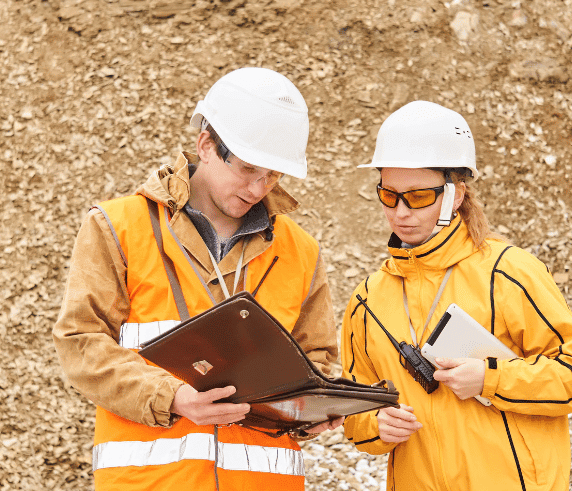 Supervise Work Permits. Two professionals in safety gear reviewing a work permit on a construction site