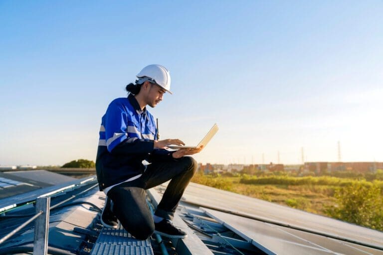 Specialist technician professional engineer with laptop and tablet maintenance checking installing solar roof panel on the factory rooftop under sunlight. Engineers holding tablet check solar roof.
